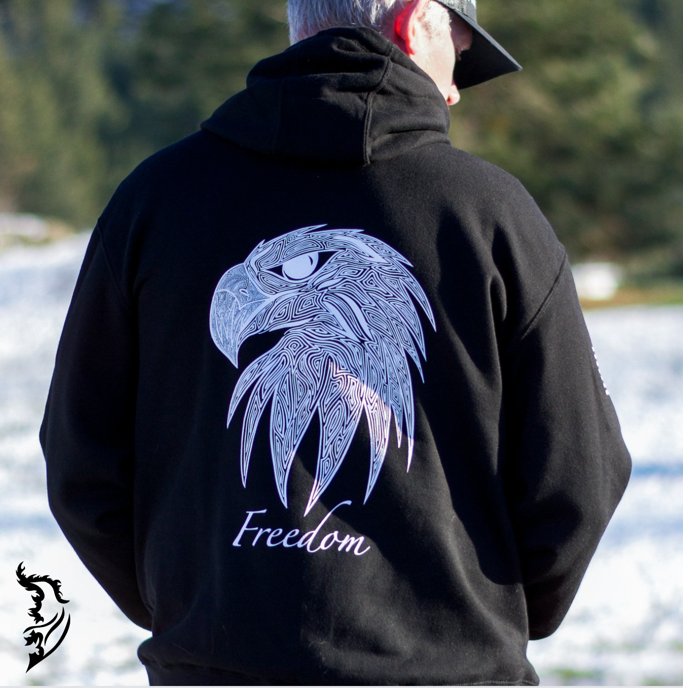 Hand-drawn eagle head with fine linework and 'Freedom' text featured on a black fleece-lined hoodie, with brand logo on the chest.
