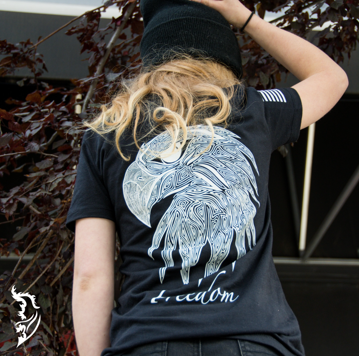 Back view of a black ladies tee with a hand-drawn eagle head design and the word 'Freedom' below, symbolizing patriotism.