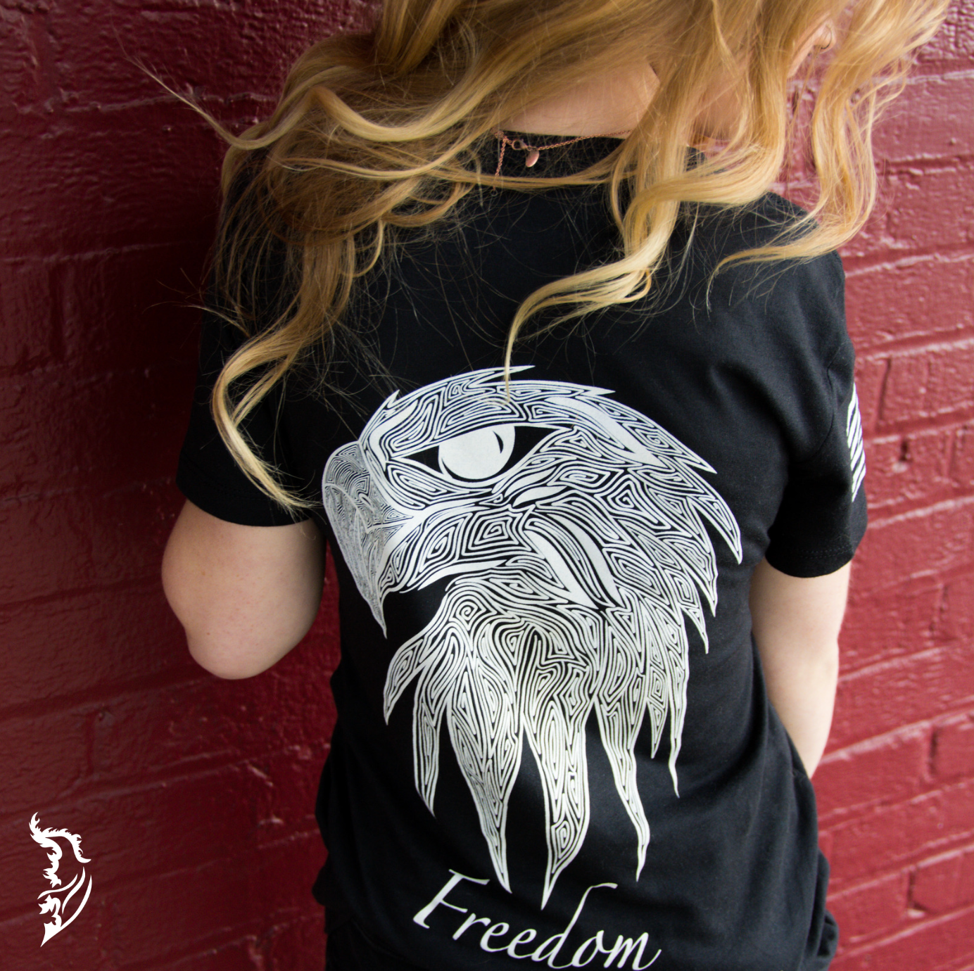 Back view of a black ladies tee with a hand-drawn eagle head design and the word 'Freedom' below, symbolizing patriotism.