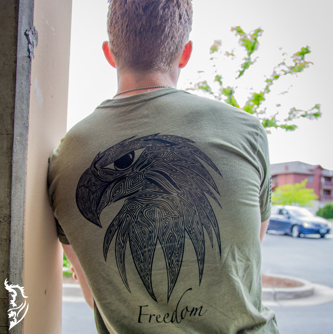 Hand-drawn eagle head with fine linework and 'Freedom' text featured on a black t-shirt, with brand logo on the chest.