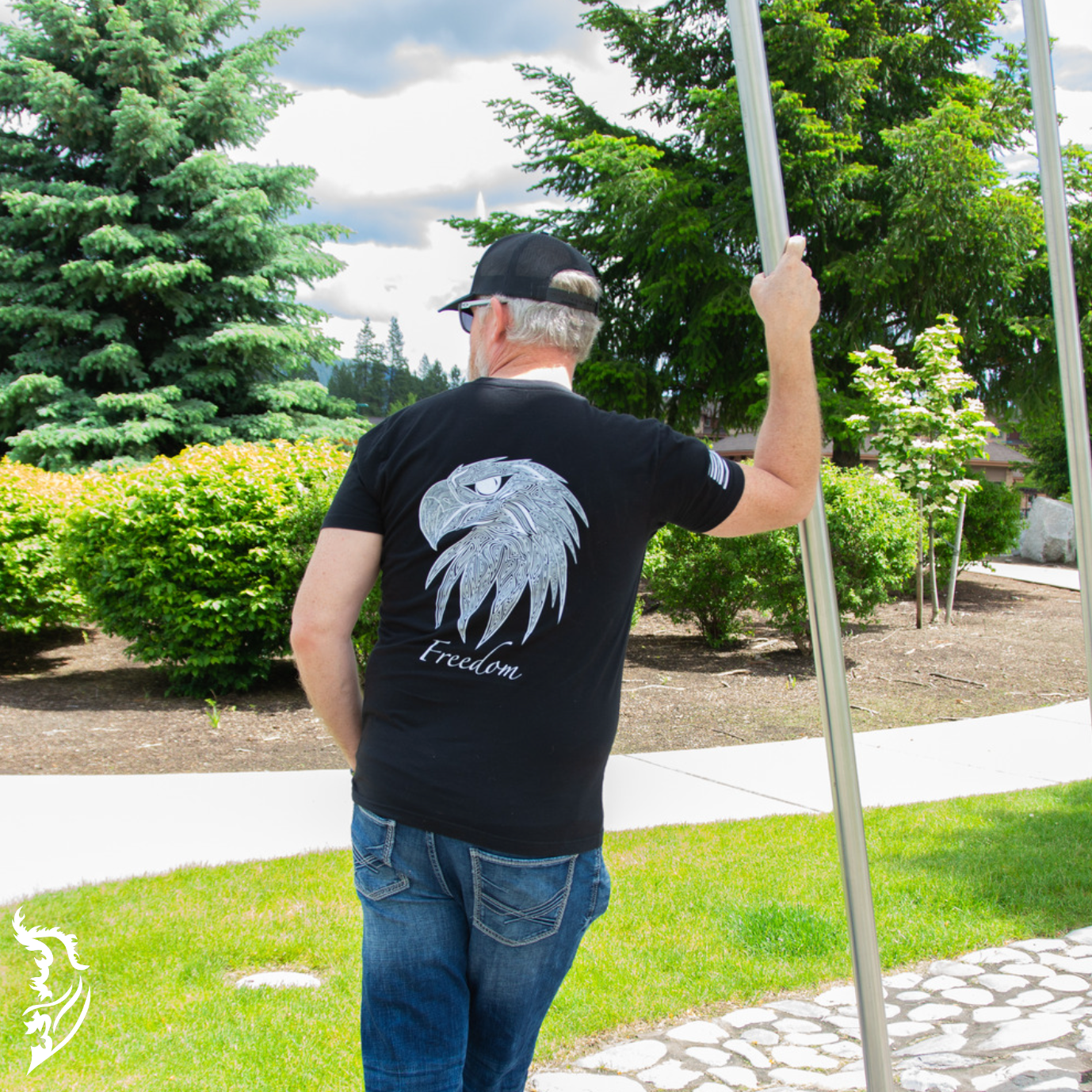 Hand-drawn eagle head with fine linework and 'Freedom' text featured on a black t-shirt, with brand logo on the chest.