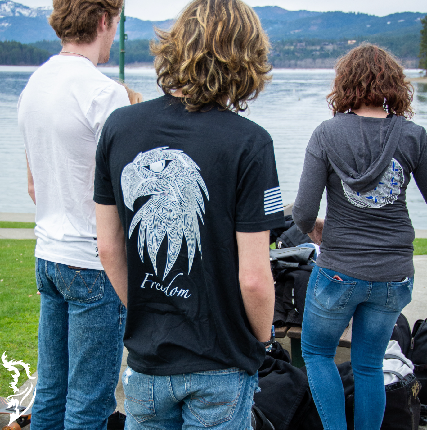 Hand-drawn eagle head with fine linework and 'Freedom' text featured on a black t-shirt, with brand logo on the chest.