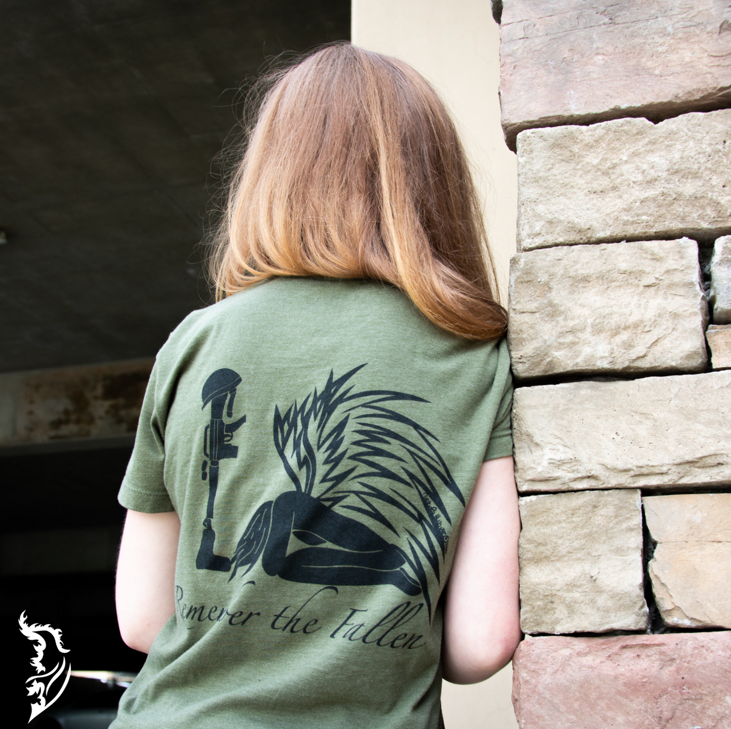 Back view of a ladies tee featuring a hand-drawn angel kneeling with wings extended, before a soldier’s boot, rifle, helmet, and dog tags in tribute to fallen soldiers.