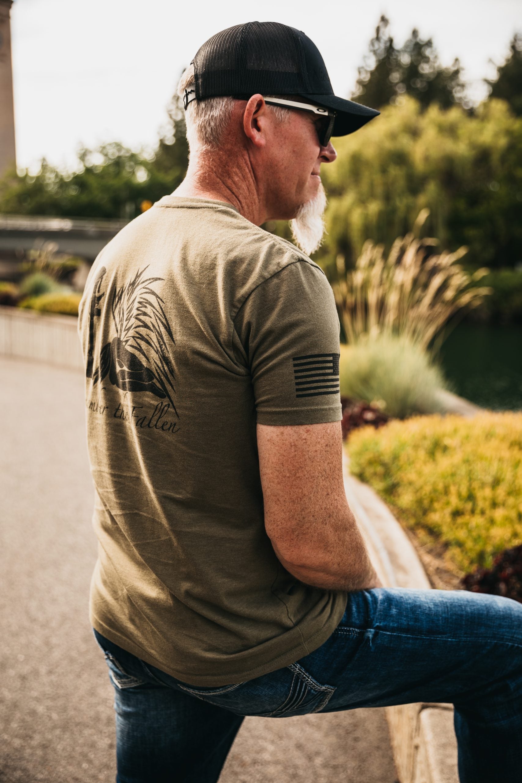 Back view of a men's tee featuring a hand-drawn angel kneeling with wings extended, before a soldier’s boot, rifle, helmet, and dog tags in tribute to fallen soldiers.