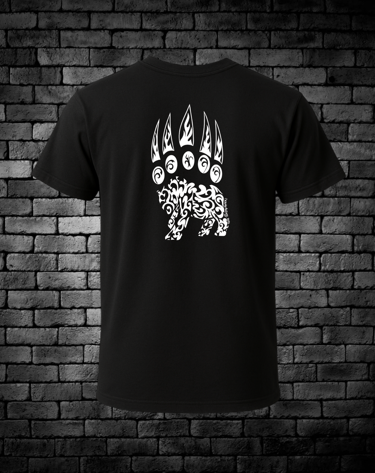 Black t-shirt with a hand-drawn white bear paw design on the back, against a brick wall background.