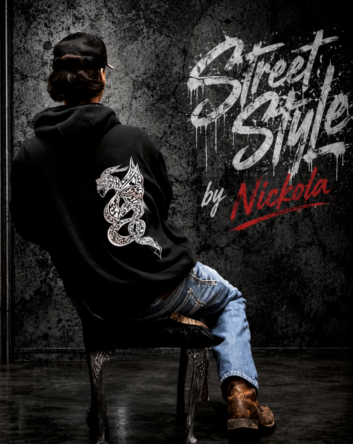 Man wearing black hoodie with hand-drawn dragon by Street Style by Nickola sitting on a vintage chair against a gritty urban streetwear background with bold graffiti-style branding and detailed white dragon artwork on the back of the hoodie.