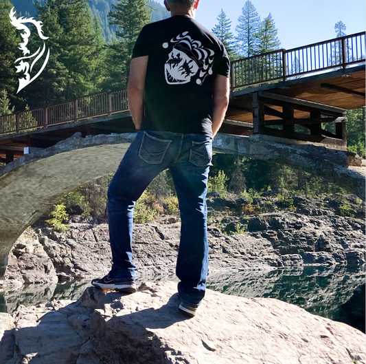 Male model wearing joker tee standing on rocks by a river