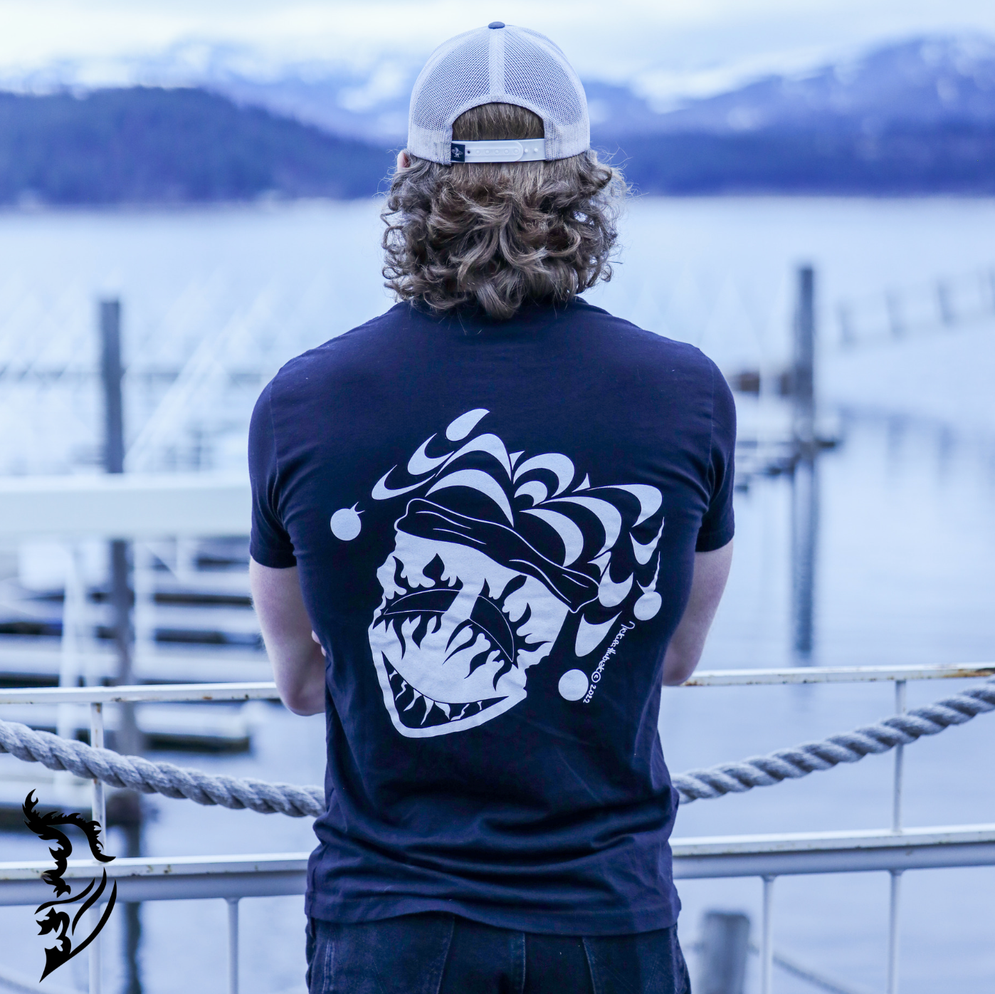Male Model wearing Joker Tee standing on bridge. overlooking the water