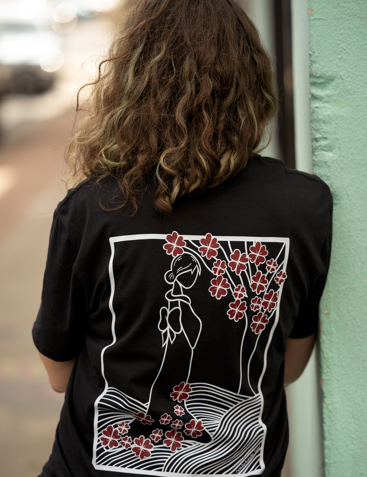 5'6" female model wearing a size small black Lady with Cherry Blossoms T-shirt featuring hand-drawn red-and-white artwork on the back.
