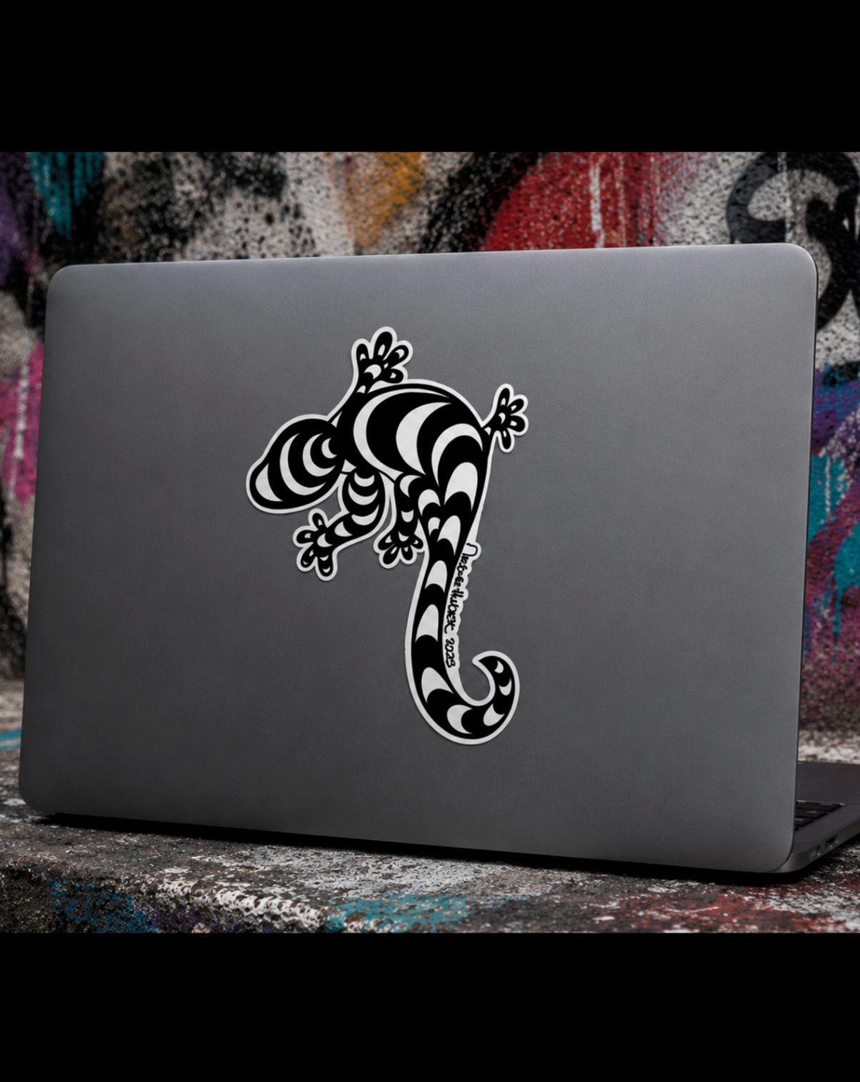 Gray laptop with a 4-inch hand-drawn black and white lizard decal sticker applied to the cover, styled in an edgy Street Style by Nickola graffiti-inspired setting.
