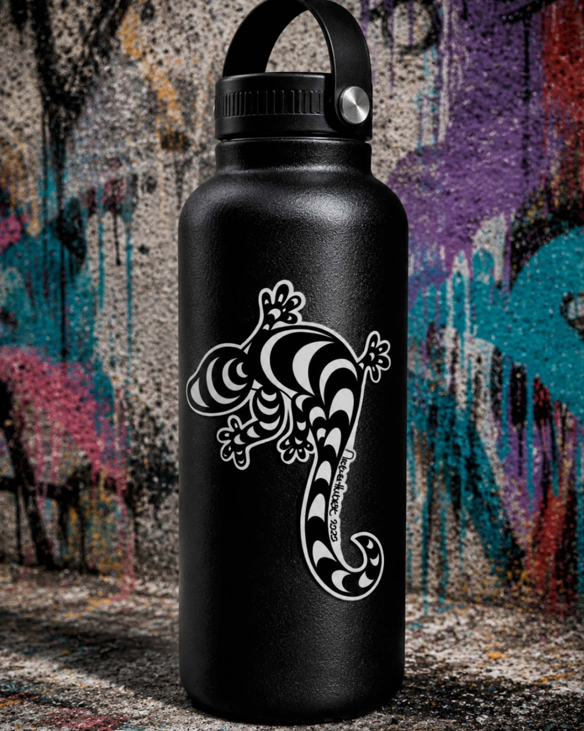 Matte black insulated water bottle featuring a black and white hand-drawn lizard UV sticker by Street Style by Nickola, photographed against a vibrant graffiti-style urban backdrop.