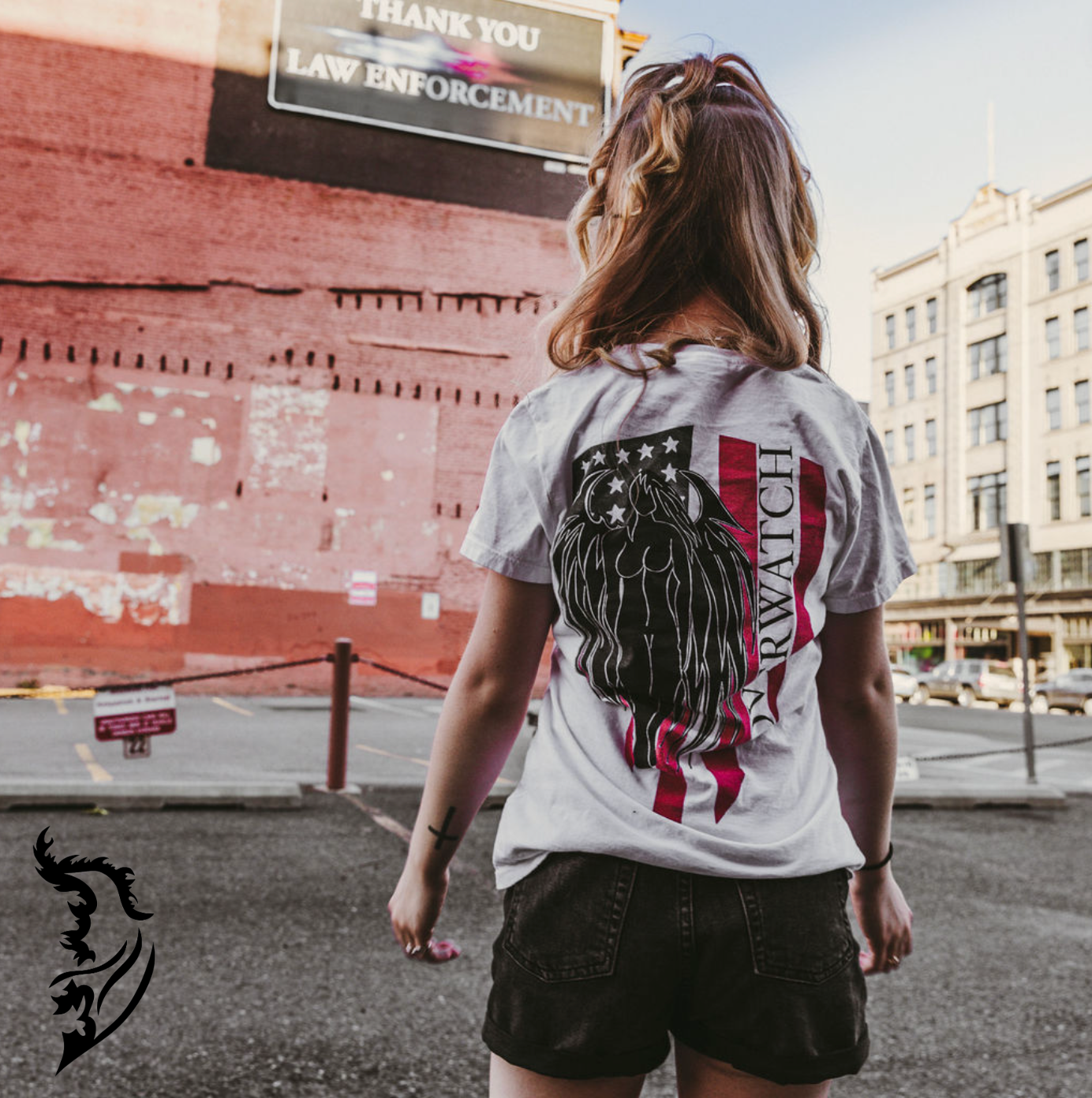 Model wearing Overwatch T-Shirt in parking lot. Showcasing Hand-drawn American Flag with Angel and Overwatch written down Flag