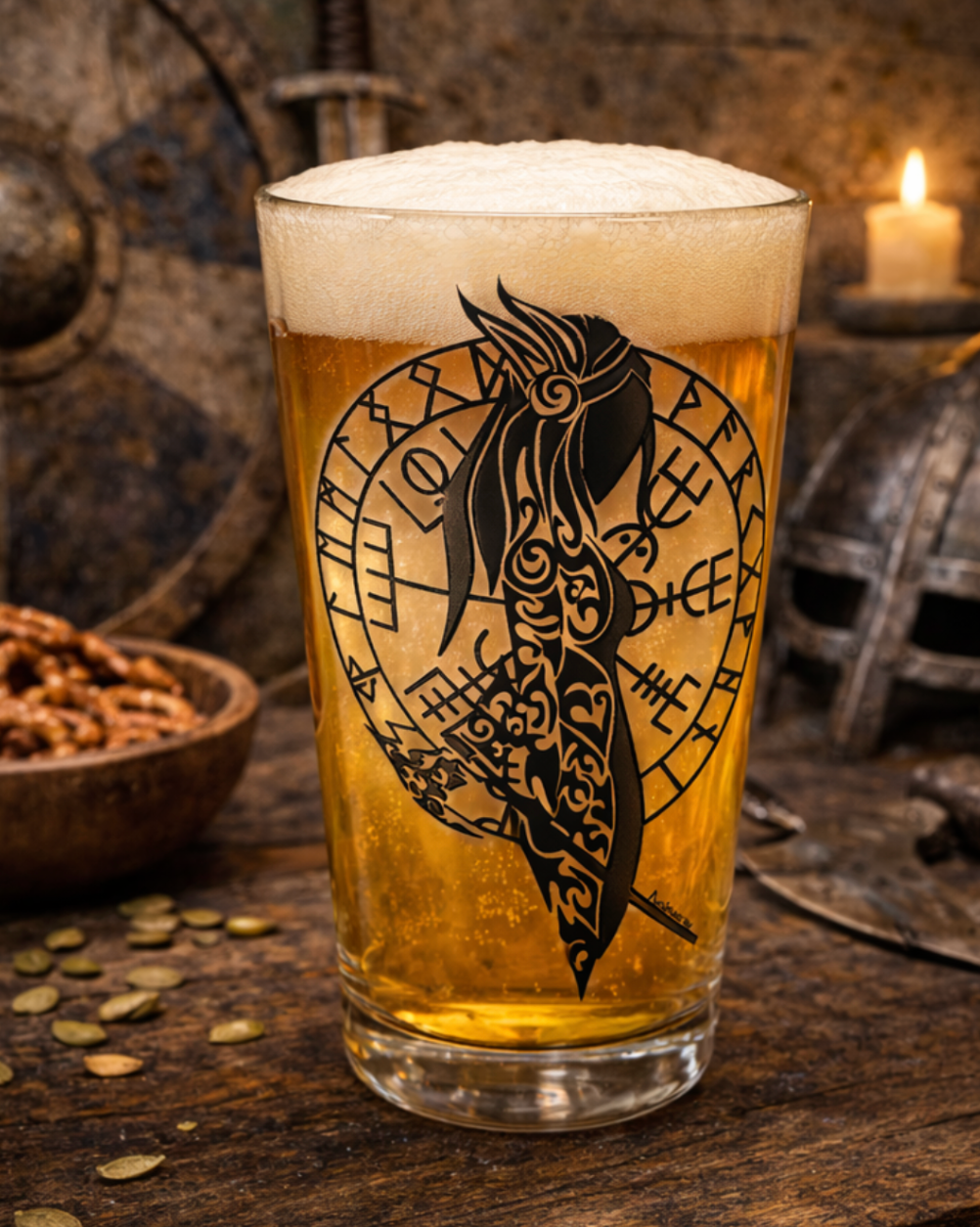 Pint glass filled with golden beer and thick foam, featuring a hand-drawn black Norse shield maiden silhouette inside a rune circle, set on a rustic wooden table with Viking helmet, shields, sword, candle, and wooden bowl in the background.