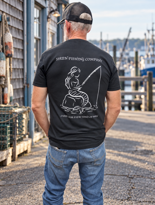 Back view of a male model in the black Siren Fishing Company T-shirt. A white mermaid holding a fishing rod fills the back design as he stands by a marina.