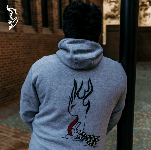 Person seen from behind wearing a gray hoodie with a hand-drawn Spark Fairy graphic on the back, standing outdoors in a brick-lined walkway with autumn leaves on the ground.