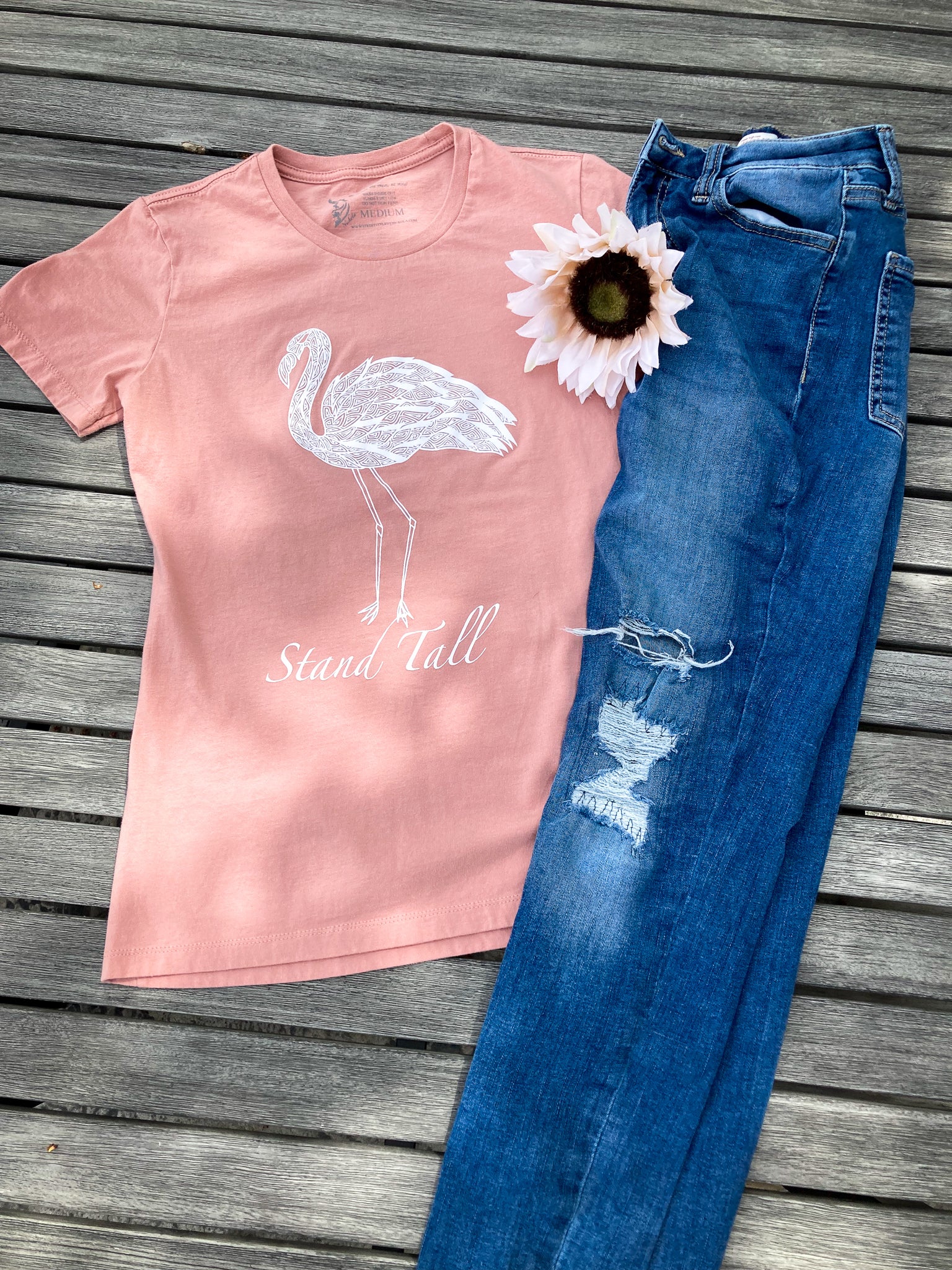 Hand-drawn Lined Flamingo with Stand Tall written below in white  on dessert pink shirt
